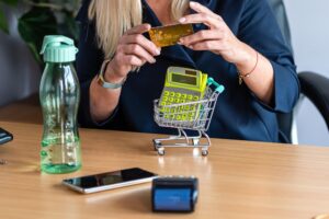 Kobieta trzymająca kartę kredytową w ręku mini wózek zakupowy w tle koncepcja płatności bez gotówki