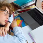 Portret kaukaski chłopiec studiuje w domu zmęczony do odrabiania lekcji