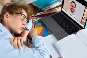 Portret kaukaski chłopiec studiuje w domu zmęczony do odrabiania lekcji