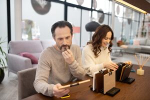 Mężczyzna i kobieta w jasnych swetrach patrząc na próbki drewna