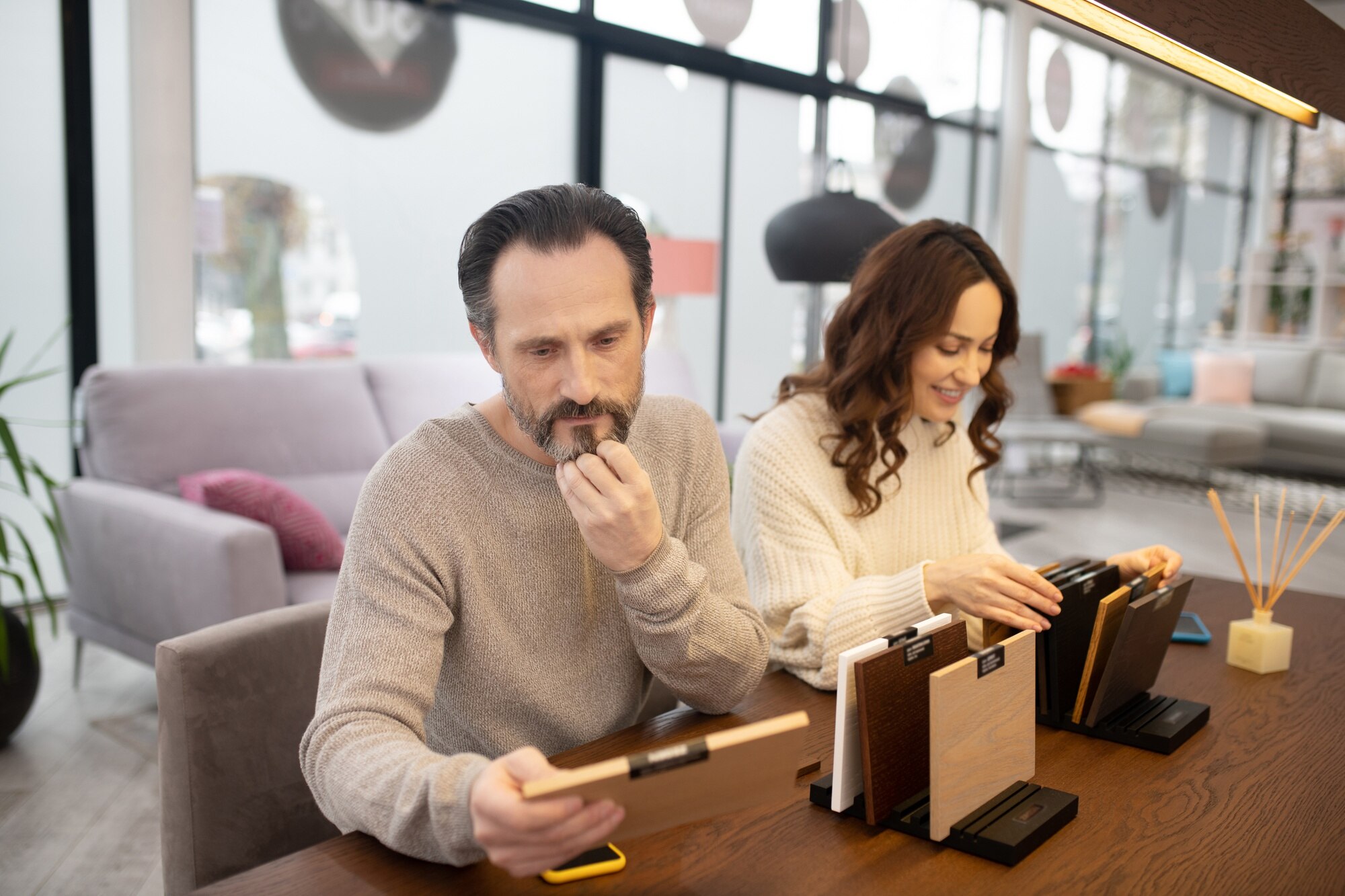 Mężczyzna i kobieta w jasnych swetrach patrząc na próbki drewna