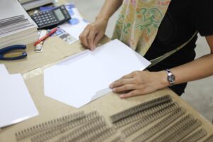 Środkowa sekcja kobiety biznesmenki składającej papier przy biurku w biurze