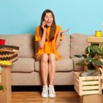 Pozytywna dziewczyna aktywnie dyskutuje o czymś, gestykuluje i trzyma telefon komórkowy przy uchu