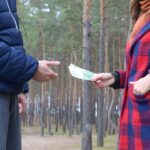 Środkowa sekcja mężczyzny dającego kobiecie papierową walutę, stojąc na lądzie