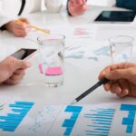 Zespół ludzi pracuje razem nad statystykami firmy w biurze. Pojęcie pracy zespołowej i partnerstwa