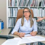 Portret wyczerpanej blond sekretarki dmuchającej z dużą ilością pracy czekającej na jej pulpicie