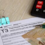 Kanadyjski formularz podatkowy, podatek dochodowy i zwrot informacji leży na stole z kanadyjskimi banknotami.