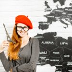 Kobieta stojąca z wieżą eiffla przy murze na tle mapy świata, marząca o wycieczce do Paryża