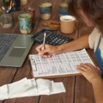 Młoda kobieta robi notatki podczas pracy z dokumentami finansowymi