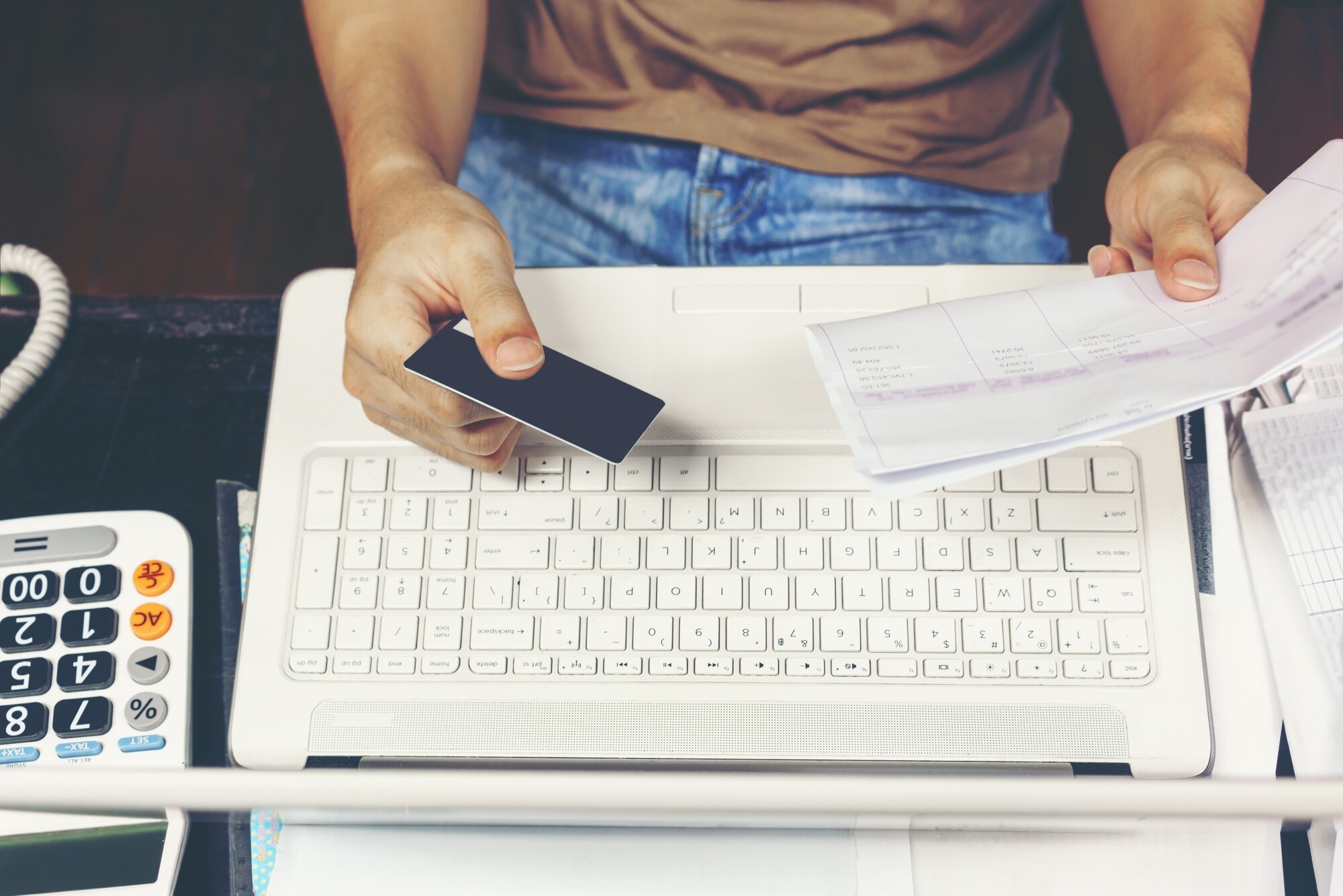 Młody człowiek używa kredytową kartę dla płacić rachunki na laptopie