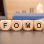 Fomo napisane na drewnianej kostce z klawiaturą kalkulator wykres monet koncepcja biznesowa