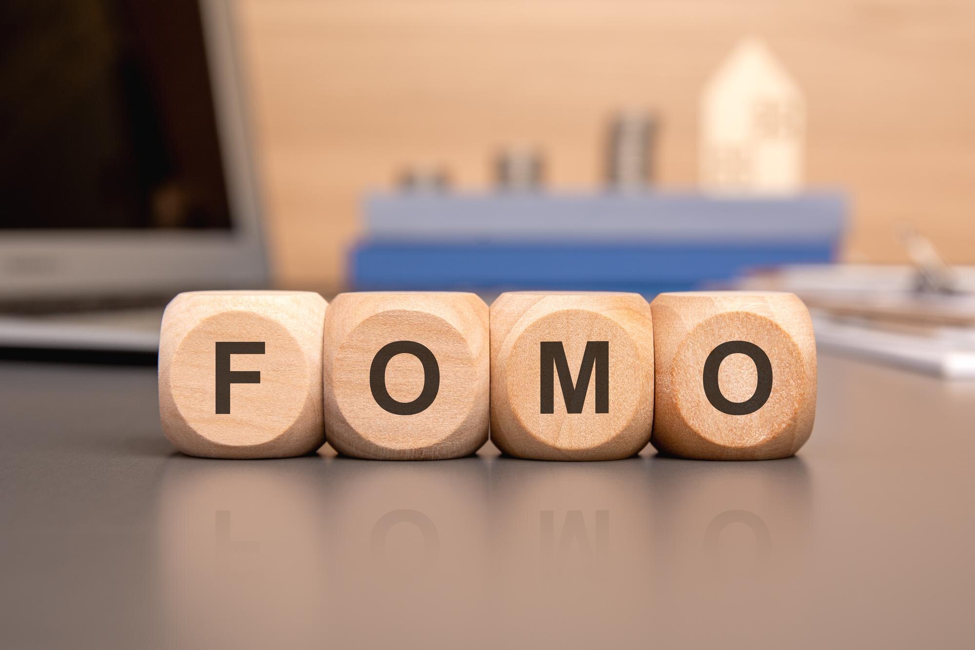 Fomo napisane na drewnianej kostce z klawiaturą kalkulator wykres monet koncepcja biznesowa