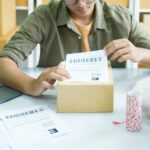 Młody przedsiębiorca pakujący produkt zamów online do wysyłki