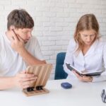 Młody pacjent testuje aparat słuchowy w gabinecie klinicznym. Pomagająca lekarz.