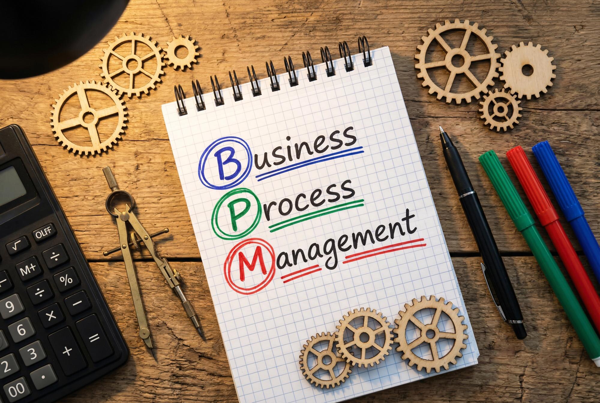 Business process management concept with notebook gears calculator and office tools on wooden desk