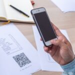 Ręka używa telefonu do zeskanowania kodu QR, aby uzyskać zniżkę na opłacenie rachunków za prąd w biurze.