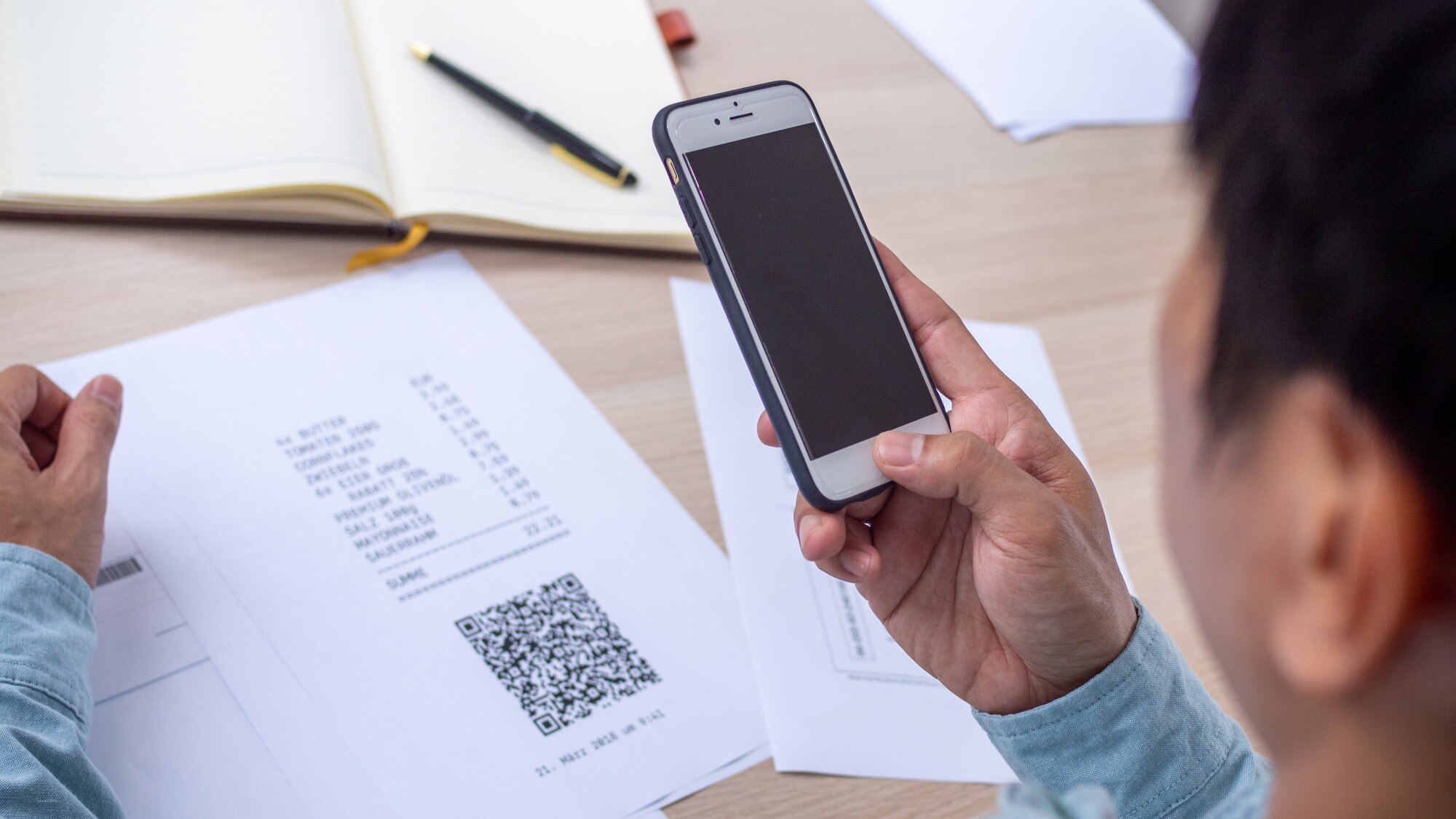 Ręka używa telefonu do zeskanowania kodu QR, aby uzyskać zniżkę na opłacenie rachunków za prąd w biurze.