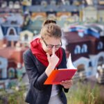 Młoda kobieta w szkłach z czerwoną falcówką w rękach, miasto widoki