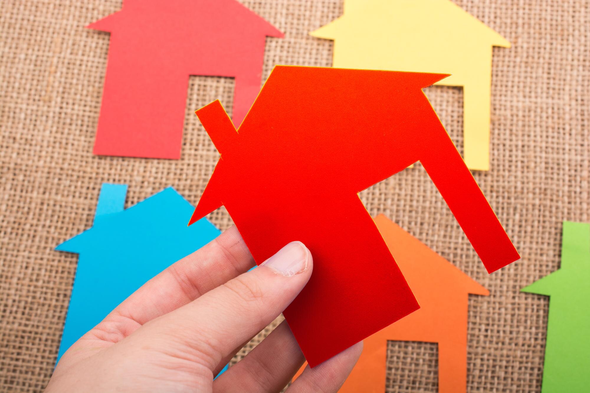 Kształt domku wycięty z kolorowego papieru na tle płótna