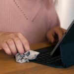 Ręce kobiety oczyszczają ekran tabletu szmatą Technologia higieniczna Closeup Osoba kobieca wyciera urządzenie cyfrowe dezynfektorem na bakterie pyłu brudu Czyszczenie laptopa Dezynfekcja przestrzeni roboczej