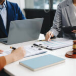 Koncepcja prawa gospodarczego, prawnicy biznesowi doradzają kobietom przedsiębiorcom w zakresie wniesienia pozwu o naruszenie praw autorskich, korzystając z laptopa i tabletu w biurze.